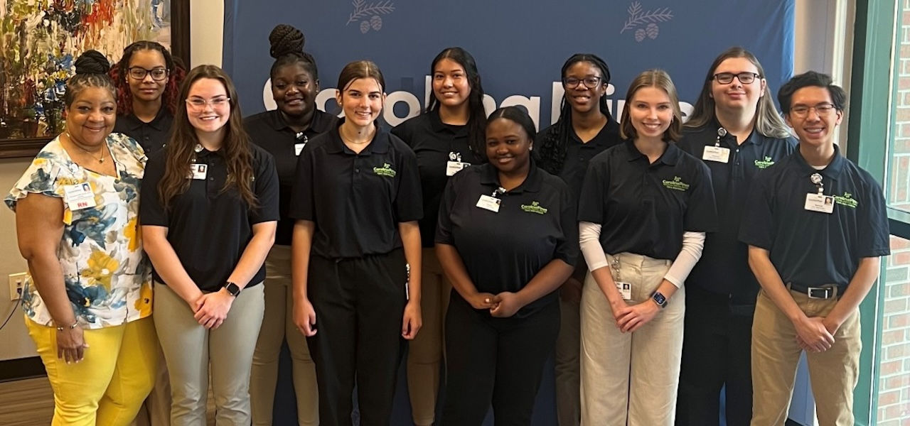 Care Apprentice Program group photo in front of blue backdrop